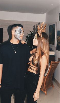 a man and woman standing next to each other in front of a television screen with their face painted