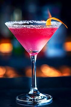 a pink cocktail with an orange slice on the rim and garnished in sugar