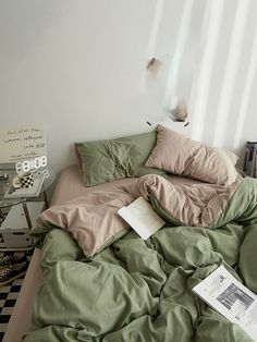 an unmade bed with green sheets and pillows