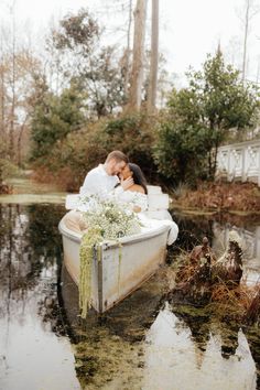 a man and woman are sitting in a boat on the water with plants growing out of it