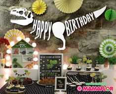 a birthday party with dinosaur decorations and desserts on the table in front of a stone wall