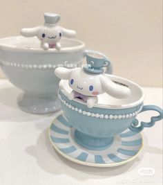 two ceramic figurines sitting on top of a saucer and bowl with an elephant in it