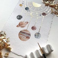 a piece of paper with gold foil on it and some planets hanging from the strings