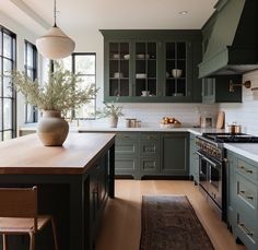 a large kitchen with green cabinets and wooden counter tops, along with a rug on the floor