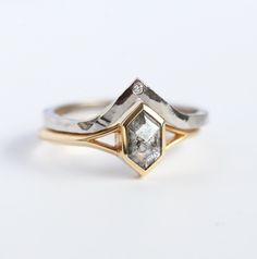 a close up of a gold and silver ring with a diamond in the center on a white background