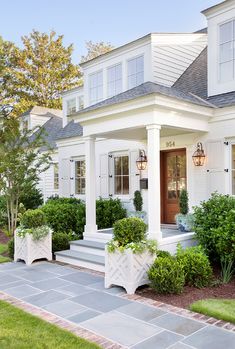 a white house with two large planters on the front porch