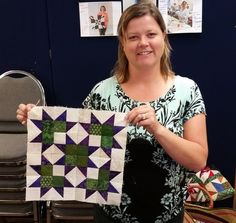 a woman holding up a piece of quilt