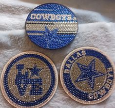 three blue and gold patches sitting on top of a white blanket next to each other