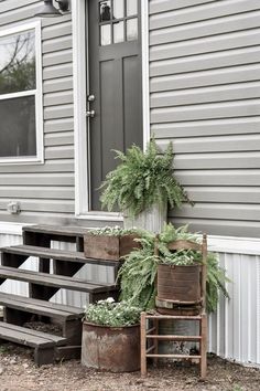 two planters sitting on the side of a house next to a wooden bench and steps