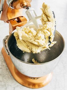 a metal bowl filled with food next to a mixer