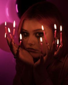 a woman is holding candles in front of her face