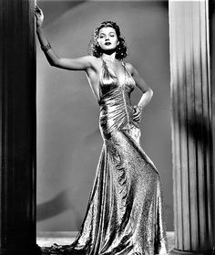 a black and white photo of a woman in a gold dress with her arms outstretched