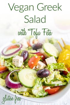 a salad with olives, cucumber, tomatoes and lettuce on a white plate