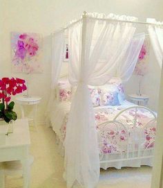 a white bed sitting next to a table with flowers on it