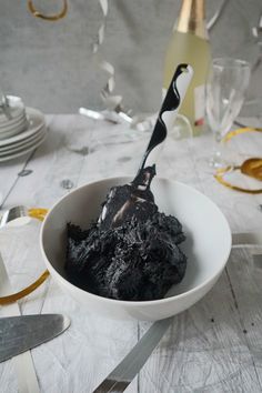 a white bowl filled with black stuff on top of a table next to silverware