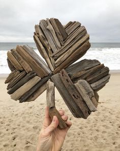 a person holding up a wooden cross on the beach