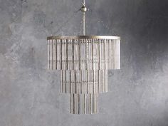 a chandelier hanging from the ceiling in a room with grey walls and concrete flooring