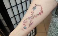 a woman with a tattoo on her arm that has flowers and leaves all over it