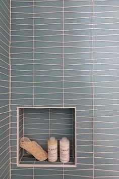 a shelf in the corner of a tiled shower