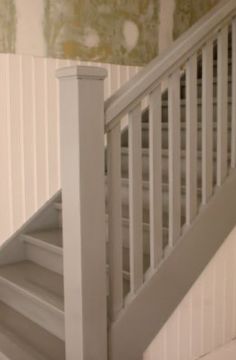 a white stair case next to a wall with green and yellow designs on the walls