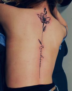 the back of a woman's lower back tattoo with flowers on her left side