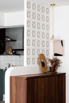 a wooden cabinet sitting next to a wall with white tiles on the top and bottom