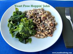 a white plate topped with beans and greens on top of a blue table cloth next to a fork