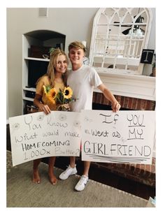 two people holding up signs in front of a fireplace