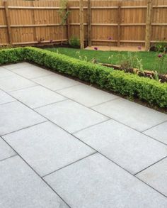 an empty patio in the middle of a yard with grass and bushes on either side