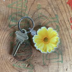 a yellow flower sitting on top of a wooden table next to a keychain