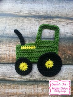 a crocheted green toy truck sitting on top of a wooden table