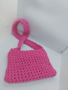 a pink crocheted purse sitting on top of a white table next to a wall