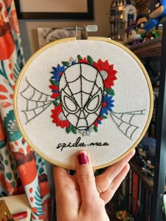 a person holding up a spider man embroidered on a hoop