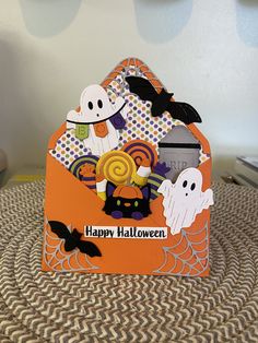 an orange halloween card with ghostes and pumpkins in the background, on top of a table