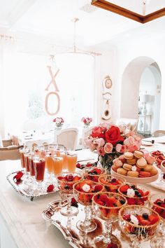 a table filled with desserts and drinks on top of a white countertop in front of a window