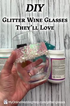 someone is holding up a wine glass with glitter on it and the words diy glitter wine glasses they'll love