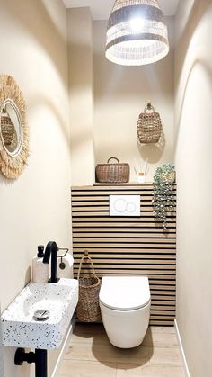 a white toilet sitting next to a bathroom sink under a light fixture in a bathroom