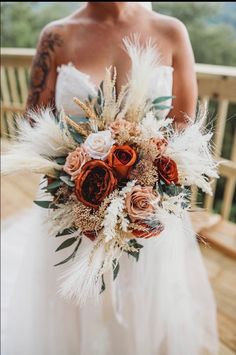 a bride holding a bridal bouquet with feathers and flowers on it's back