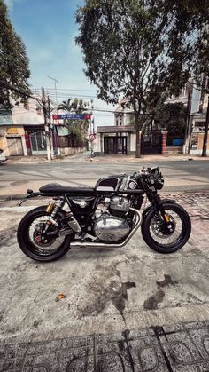 a motorcycle is parked on the side of the road in front of some buildings and trees