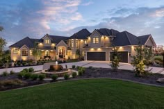 a large house with lots of lights on it's windows and landscaping around the front yard