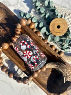 a glass jar sitting on top of a wooden table next to some wood beads and greenery