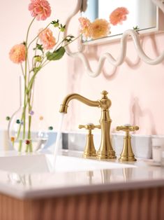 a bathroom sink with gold faucet and flowers