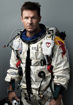 a man in an astronaut suit with his helmet and goggles around his neck is posing for a photo