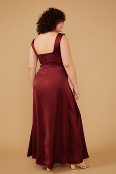 a woman in a long red dress with her back to the camera, looking down