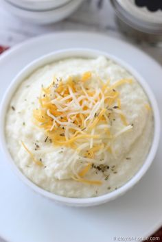 a white bowl filled with mashed potatoes topped with cheese