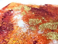 an orange and gold piece of food on a white tablecloth with some green spots