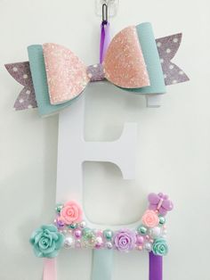 the letter e is decorated with pastel colors and sequins, as well as bows