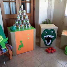 two cardboard boxes with dinosaur faces on them, one is green and the other is orange