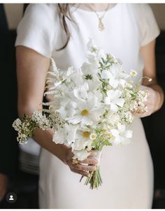 a woman holding a bouquet of white flowers