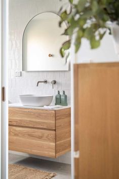 a bathroom sink sitting under a mirror next to a wooden cabinet